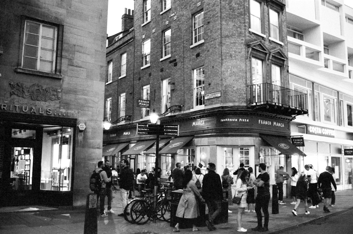 People gathering outside cafés in Cambridge Market Square